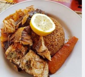 a white plate of food with a lemon on top at J'adore House in Abémé
