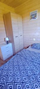 a bedroom with a bed and a dresser with a lamp at Domki Letniskowe SOHO in Bobolin +2 photos