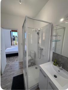 a white bathroom with a shower and a sink at Chambre avec salle de bain privé in Neuvic