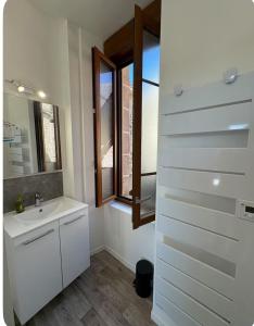 a white bathroom with a sink and a window at Chambre avec salle de bain privé in Neuvic