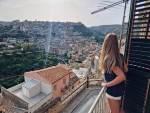 a woman standing on a balcony looking at a city at Reusia Holiday Home in Ragusa