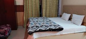 a bed with a black and white comforter on it at Friends cottage in Coonoor