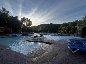 a swimming pool with blue chairs and chairs in it at Cozy Log Cabin, hot tub, pool table, pool access in Gatlinburg