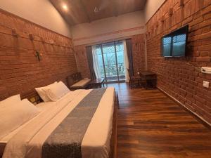 a bedroom with a large bed and a brick wall at Hide Away Resort in Jhārgrām