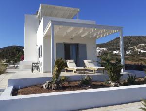a white house with a pergola and a patio at Villa Ploes in Agios Georgios