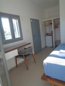 a bedroom with a bed and a desk and a window at Villa Ploes in Agios Georgios