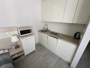 a small kitchen with white cabinets and a microwave at Apartment Czarna Góra Resort ISCHGL 30, Sienna in Sienna