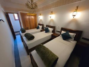 a bedroom with three beds with green pillows at Dar AWRABIA in Fez