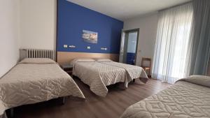 sypialnia z trzema łóżkami i niebieską ścianą w obiekcie Hotel Splendor w Grado