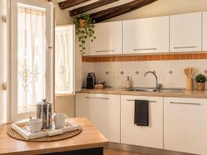 a kitchen with white cabinets and a wooden table at Dimora Leonardo. Centro Storico. in Lucca