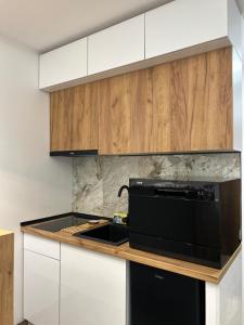 a kitchen with a black microwave and wooden cabinets at Apartman Porta 108 in Kruševac