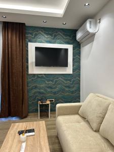 a living room with a couch and a tv on a wall at Apartman Porta 108 in Kruševac