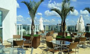 a patio with tables and chairs and palm trees at Flat Brasília - Setor Hoteleiro Norte in Brasília