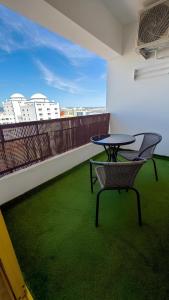 a table and a chair on a balcony with green grass at Rocha Paradise Apartment in Portimão