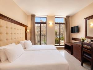 a hotel room with two beds and a television at The Annexe - by Gloria Hotel in Jerusalem