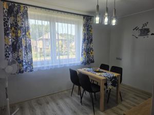 a dining room with a table and chairs and a window at Apartament Stokrotka in Olszyny