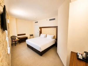a bedroom with a bed and a table and a desk at The Annexe - by Gloria Hotel in Jerusalem