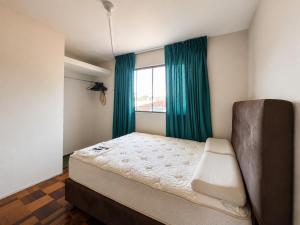 a bedroom with a bed with green curtains and a window at Lanni House in Huanchaco