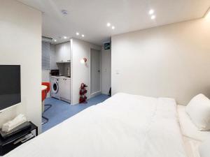 a bedroom with a large white bed and a kitchen at 호텔느릿 in Seoul