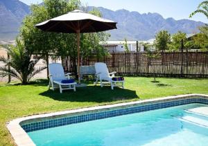 two chairs and an umbrella next to a swimming pool at Eikelaan Farm Cottages in Tulbagh