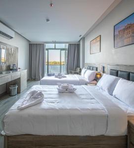 a large bedroom with two beds and a large window at Regency Nile Hotel Assuit in Al Ḩamrāʼ