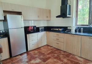 a kitchen with a white refrigerator and wooden cabinets at Beach villa South Goa in Arossim-Cansaulim