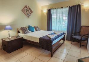a bedroom with a bed and a chair and a window at Beach villa South Goa in Arossim-Cansaulim
