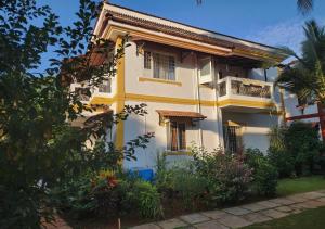 a yellow and white house with a balcony at Beach villa South Goa in Arossim-Cansaulim
