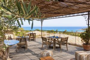 a patio with tables and chairs and the ocean at Hôtel & Spa A Cala - Suites Piscines Privées - Adults Only in Conca