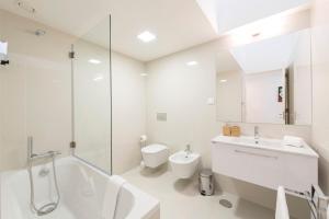a white bathroom with a tub and a toilet and a sink at Bright Downtown Apartment in Porto