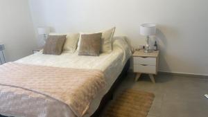 a bedroom with a bed and a table with a night stand at Paseo Cibeles departamento in Villa Carlos Paz +1 photo