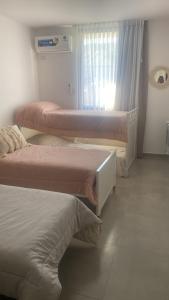 a room with three beds and a window at Paseo Cibeles departamento in Villa Carlos Paz