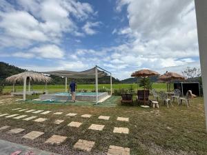 a man standing next to a pool with a tent at Homestay Kamila Mersing in Mersing