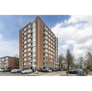 a tall building with cars parked in a parking lot at Apartment with skyline view in Eindhoven