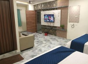a hotel room with a bed and a flat screen tv at HoTEL MADHAVI ELITE in Vijayawāda