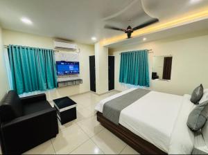 a bedroom with a bed and a couch and a television at HoTEL MADHAVI ELITE in Vijayawāda