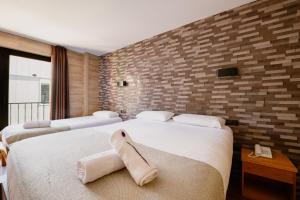 two beds in a room with a brick wall at Cal Ruiz in Pas de la Casa