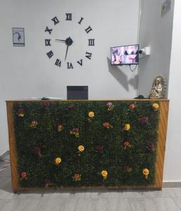 a clock on a wall with flowers on it at Hotel Matias Real in Buga