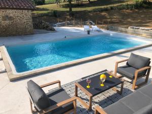 a swimming pool with two chairs and a table next to it at Pigeonnier La Carole 35m2 in Monlezun