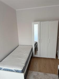 a white bedroom with a bed and a cabinet at Apartament Bald1 in Kąty Wrocławskie