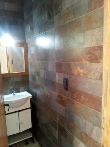 a bathroom with a sink and a tiled wall at Tano in Villa Gesell