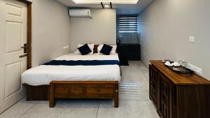 a bedroom with a bed and a wooden dresser at AIDAN RESIDENCY - AC Premium Rooms in Alwaye