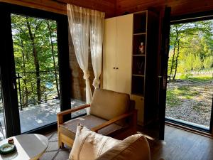 a living room with a chair and a table and windows at Love Cabin in Slatina Varoš