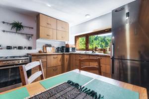 a kitchen with a table and a stainless steel refrigerator at Ski House Szczyrk - Solisko in Szczyrk