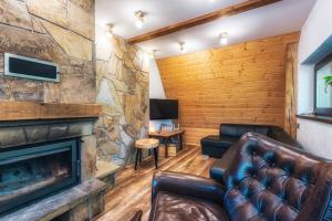 a living room with a fireplace and leather furniture at Ski House Szczyrk - Solisko in Szczyrk