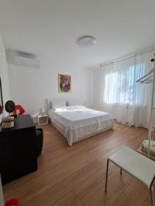 a white bedroom with a bed and a wooden floor at Casa Timavo in Ronchi dei Legionari