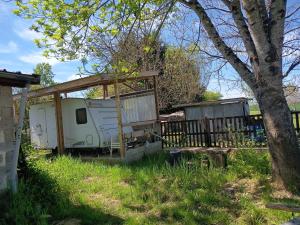 an rv parked in a yard next to a tree at Petit cocon in Laignes