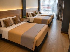 a hotel room with three beds and a window at BRIX Hotel in Arequipa +2 photos