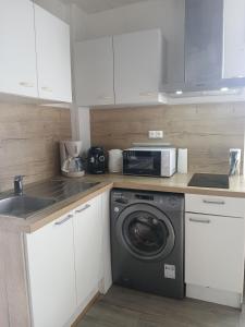 a kitchen with a washing machine and a microwave at Maison proche château in Bressuire +21 photos