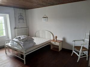 a bedroom with a white bed and a chair at Maison proche château in Bressuire